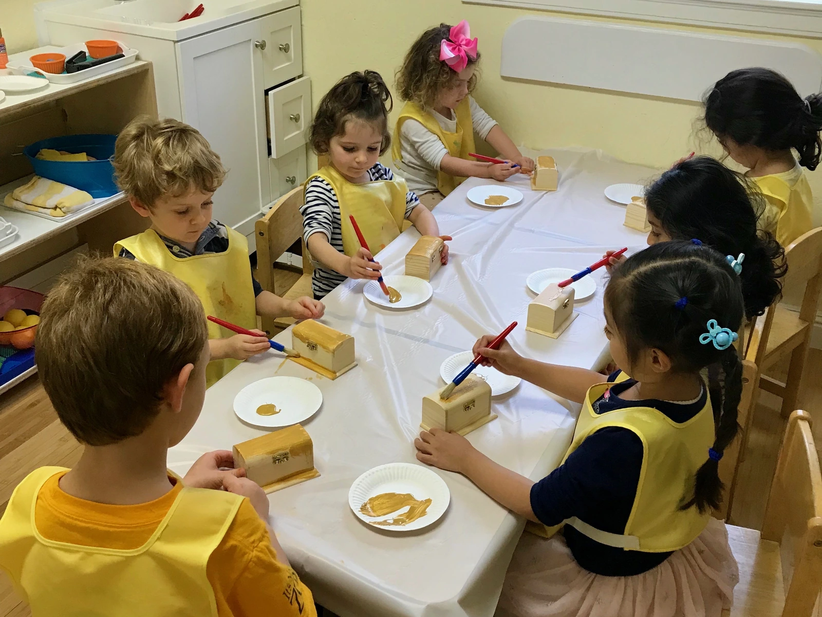 Children in aprons working together at the art table