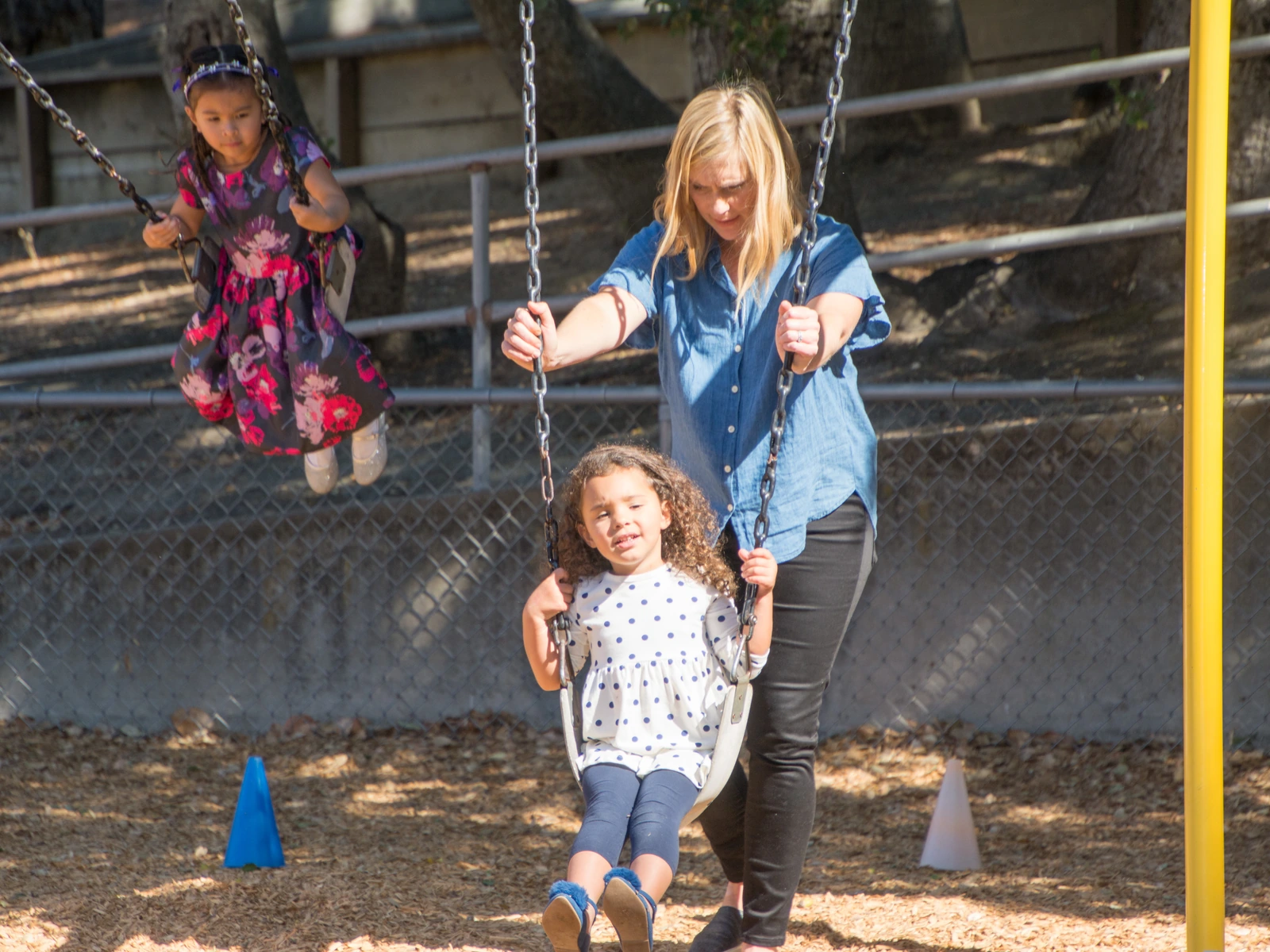 A child on the playground swing with a teacher